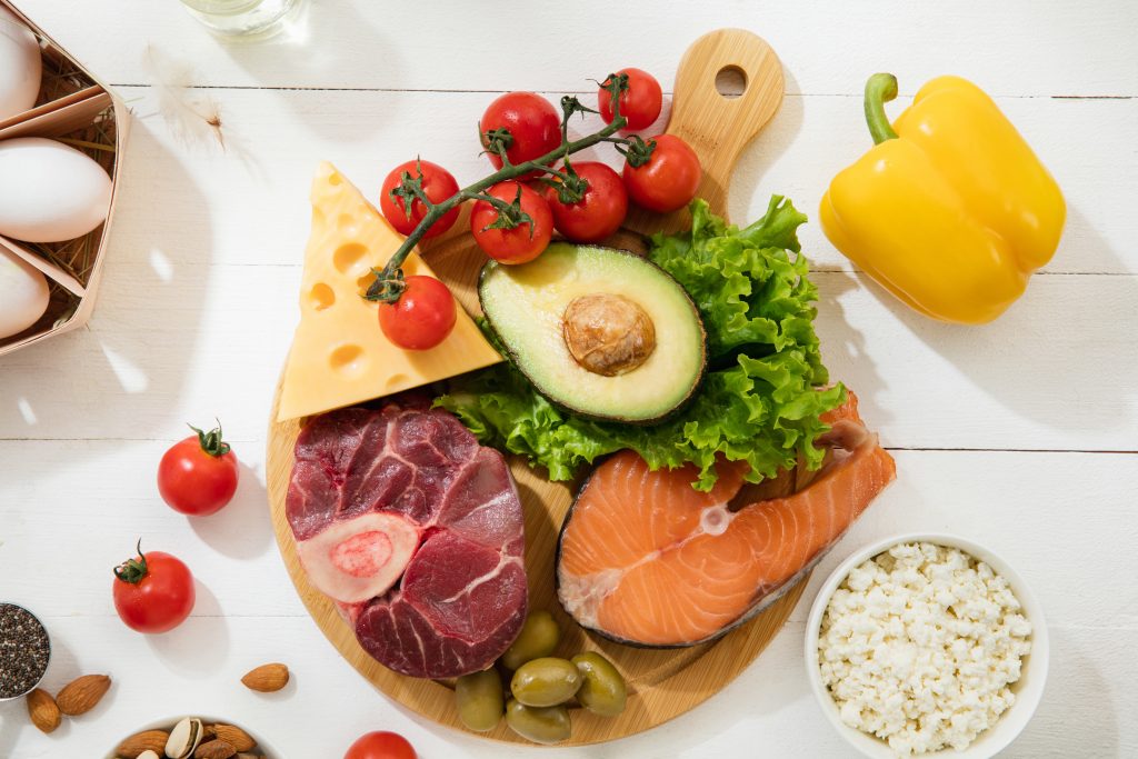 Ketogenic low carbs diet - food selection on white wooden background. Balanced healthy organic ingredients of high content of fats. Nutrition for the heart and blood vessels. Meat, fish and vegetables.