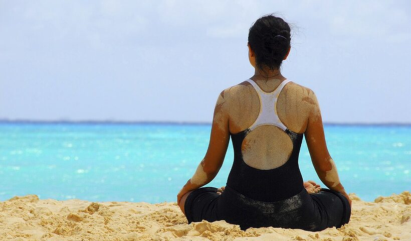 Person practicing meditation and yoga on a beach