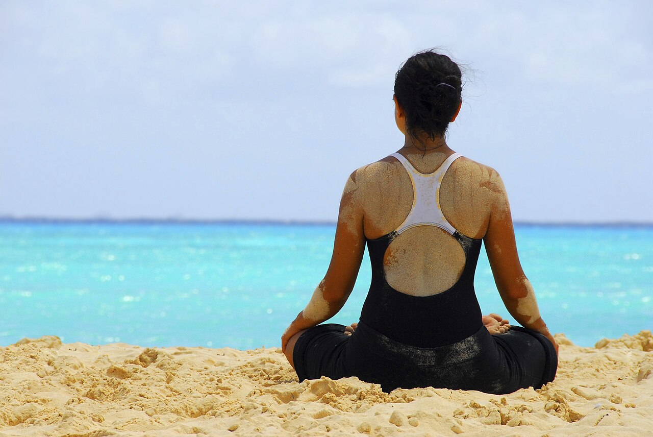 Person practicing meditation and yoga on a beach